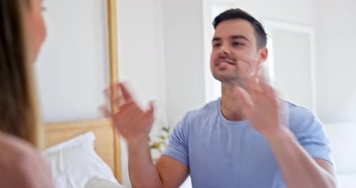 Man Gesturing While Talking to Woman in Bedroom
