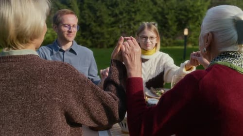 Family Holding Hands in Garden Before Meal