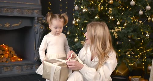 Mother and Child Opening Christmas Gift by Tree