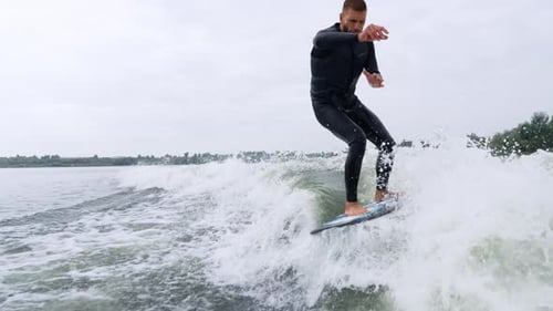 Surfer Skillfully Rides a Wave Showcasing Balance and Agility on a Calm Water Surface