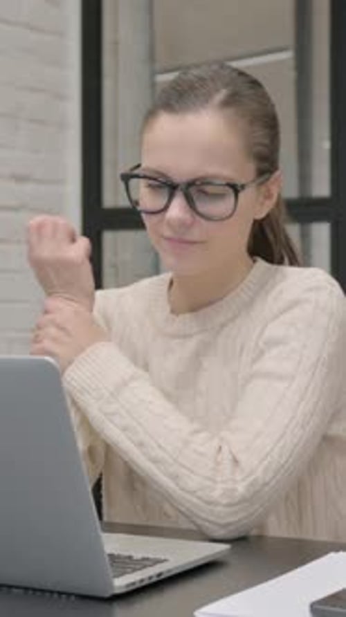 Woman Massaging Sore Wrist at Desk