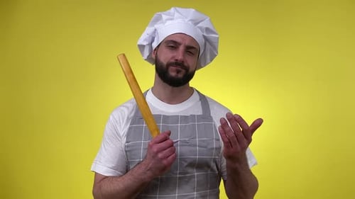 Chef with Rolling Pin in Front of Yellow Background