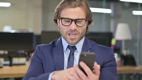 Businessman Reacts Positively to News on Smartphone