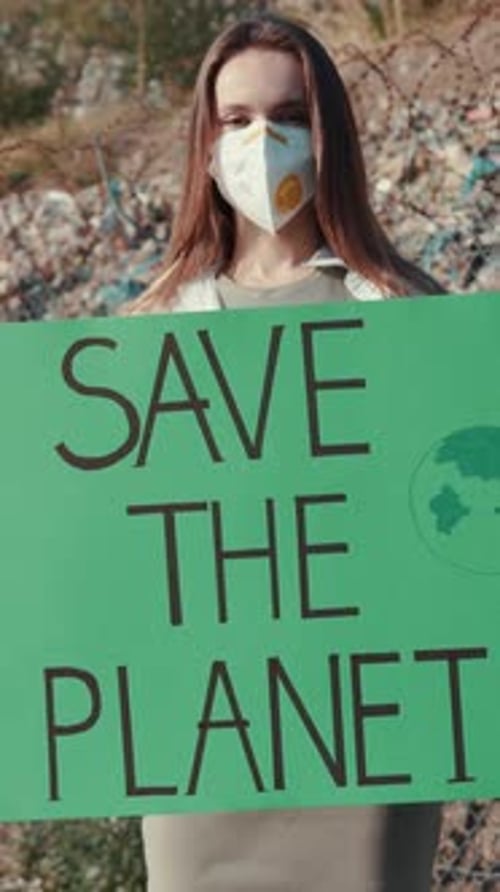 Woman Holding Save the Planet Sign in Urban Setting