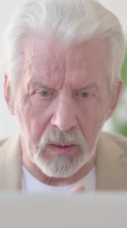 Close Up of Old Man Talking on Video Call on Laptop in Office, Vertical Video