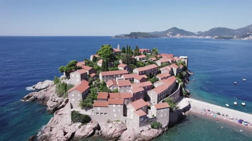 A drone flies over the island of Sveti Stefan on a sunny day in Montenegro