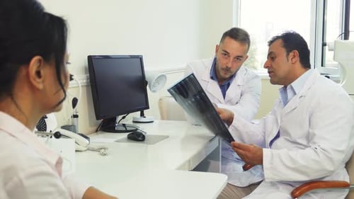 Doctors Analyze XRay Images While Consulting a Patient in a Bright Office