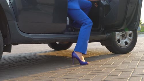 Slim and Wellbuilt Woman Stands on Pavement From Car and Close the Door