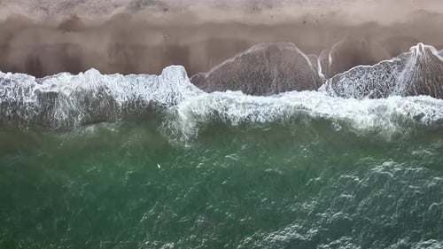 Aerial shooting of sandy beach and ocean with waves from above. The sea and beach from above, waves
