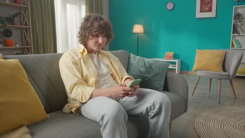 Young Man Using Phone on Couch at Home