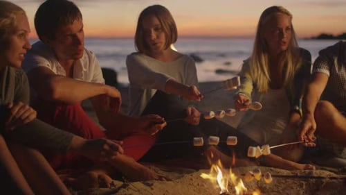 Friends Roast Marshmallows at Beach Bonfire at Sunset
