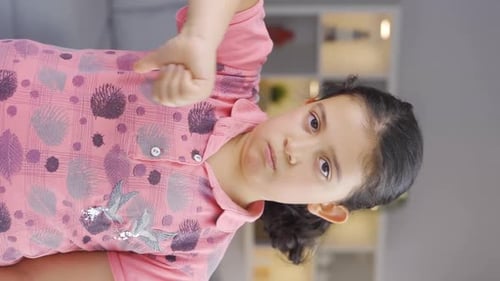 Vertical video of Girl child looking at camera with a negative expression.