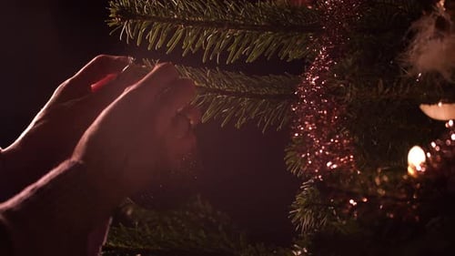 Woman's hands hanging ornament ball decoration on Christmas tree. Close up handheld