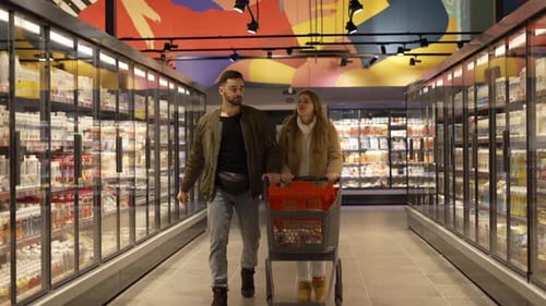 Rivne, Ucrânia, 14 de outubro de 2022 Um jovem casal com um carrinho de compras escolhe produtos em uma loja