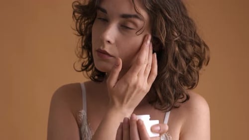 Closeup of a Young Woman Applying Cream to Her Face Spa Treatment Concept