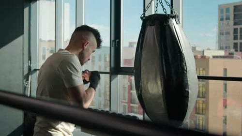 Man Boxing Heavy Bag in Gym with City View