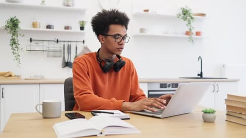 Man Studying at Table With Laptop and Books