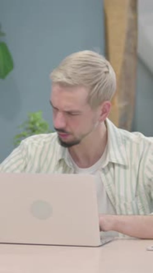 Young Adult Man Massaging Stiff Neck at Desk