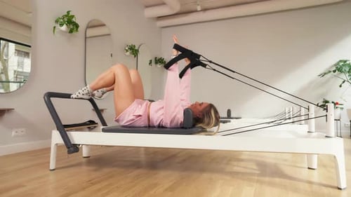 Woman Exercising on Pilates Reformer Machine