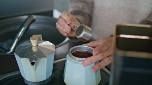 Una mujer sirve café con las manos en una olla de moka preparando la bebida para prepararla de cerca