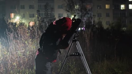 Person Engaged in Astronomical Viewing in City Environment at Night Enthusiast with Optical Device