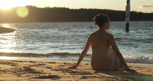 Woman Sitting on Beach at Sunrise