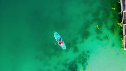 Two Adults Paddle Boarding on Turquoise Water