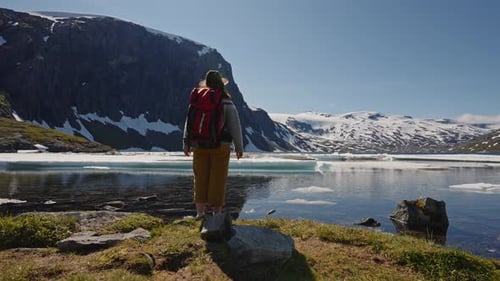 Active Woman with Red Backpack Hiking with Scenic View on Snow Capped Mountain Peaks of Norway