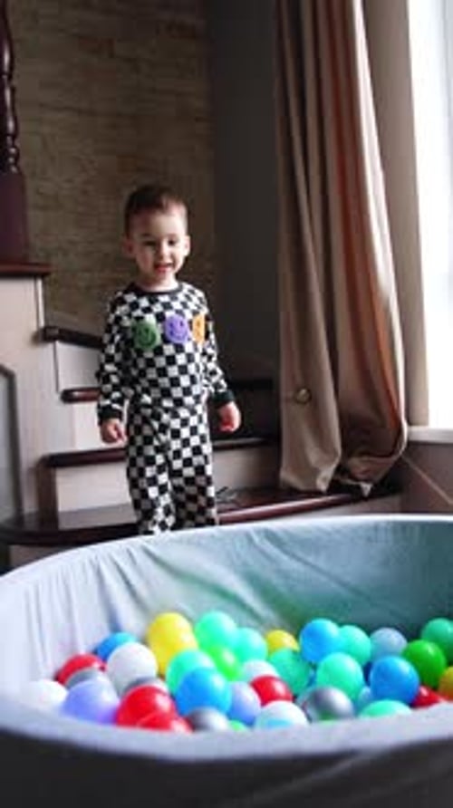 Smiling Child Jumps Into Ball Pit Indoors