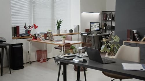 Interior of Modern Office Featuring Desks with Laptops, Documents and Notebooks