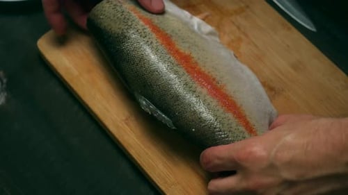 Hands Preparing Fish on a Cutting Board