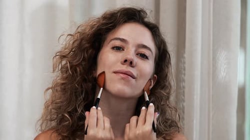 Woman Applies Makeup Brushes to Her Face