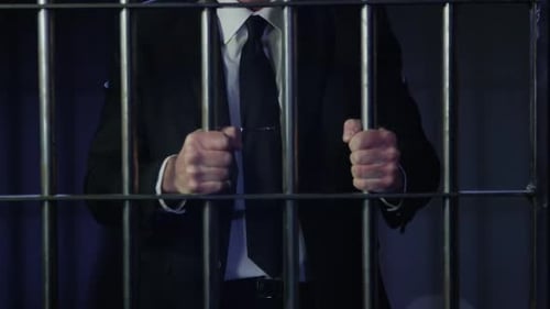 White collar crime - man struggling with the bars of his prison cell - financial crime HD