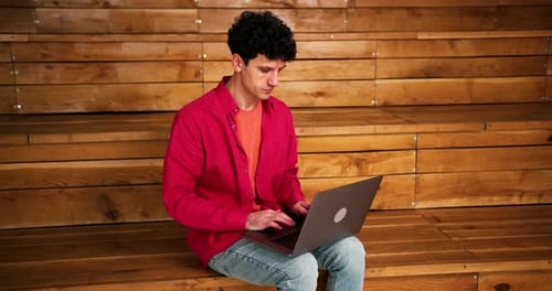 Man Works on Laptop While Sitting on Steps