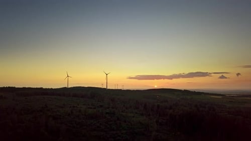 Silhouetten von Windkraftanlagen auf einem Hügel bei Sonnenuntergang. 4k Drohnenaufnahmen.
