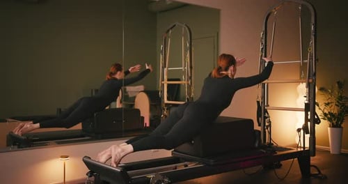 Woman on Pilates Machine Gripping Bar in Studio