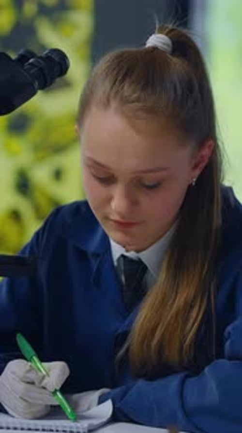 Girl in Lab Coat Using Microscope and Writing