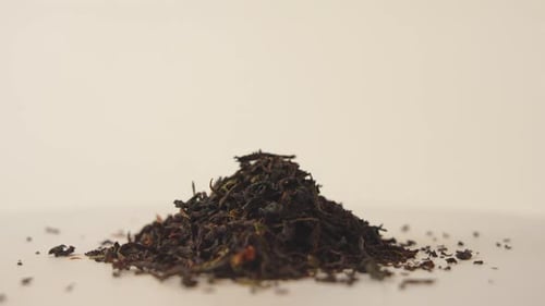 Close-up shot of a pile of dried black tea leaves rotating on bright background. 4K. Macro.
