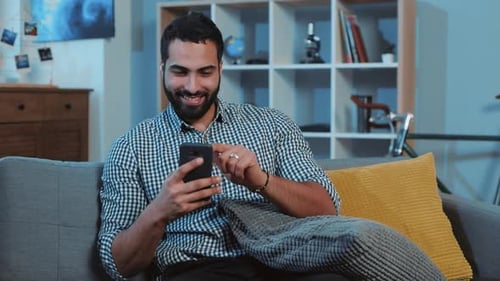 Man Relaxing on Couch Using a Mobile Phone