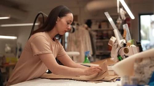 Side View of Female Designer Preparing Cardboard Sewing Patterns Meticulously Arranging Them on