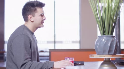 Young male adult and young female adult sitting at a table and talking with drinks on table in a Jap