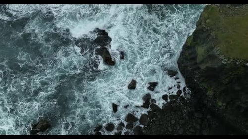 Aerial view of crispy waves breaking on the cliffs along the coast in Iceland.