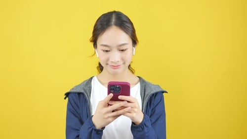 Woman Smiling While Looking at a Smart Phone