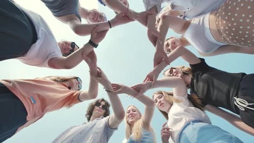 Group of Young Students Forming a Circle with Their Hands Together Outdoors Low Angle View