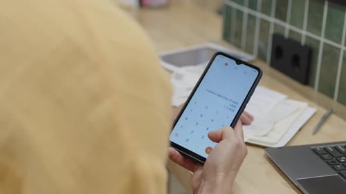 Supermarket Owner Counting Daily Revenue on Smartphone
