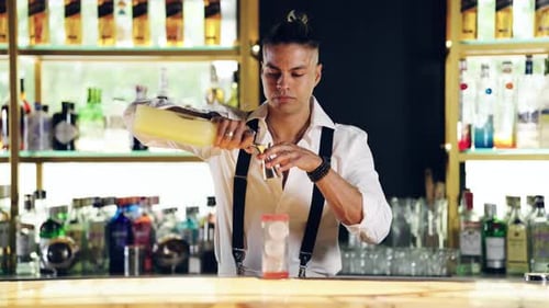 Barman professionnel préparant un cocktail artisanal avec un jigger