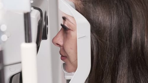 Attentive optometrist examining beautiful female patient with slit lamp in ophthalmology clinic. Opt