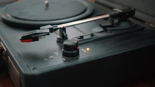 Hand Turns Knob on Black Portable Turntable