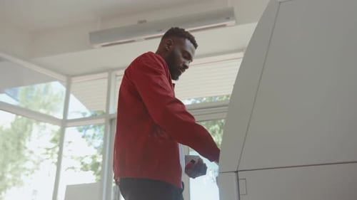 African American Attractive Man Getting Money From an ATM Cash Machine with a Credit Card Inside the
