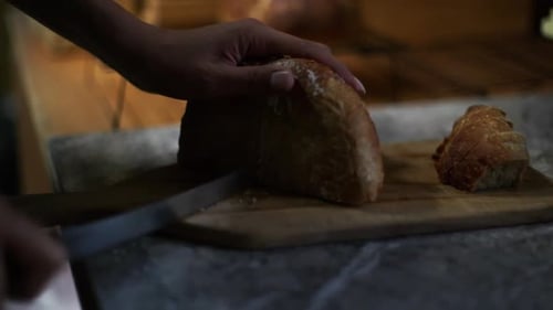 Someone cutting a loaf of bread on a board